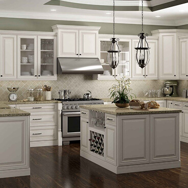 Traditional American-style framed kitchen cabinets in an elegant white finish with crown molding, pendant lights, and central island