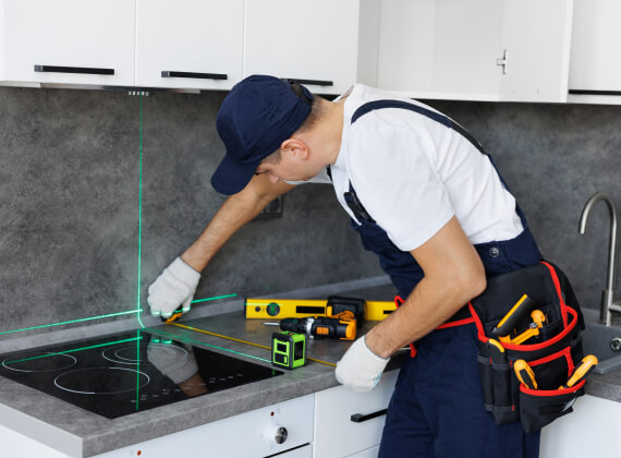 Technician using 3D laser measuring tools to verify kitchen cabinet dimensions for precise design fitment