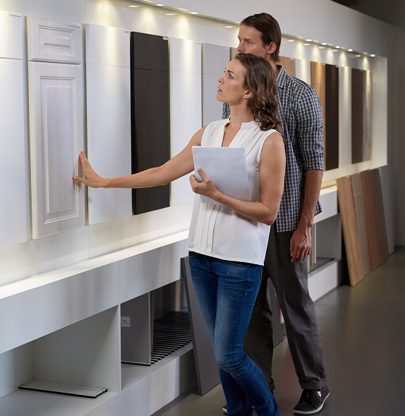Woman and man examining cabinet door samples at a kitchen design showroom