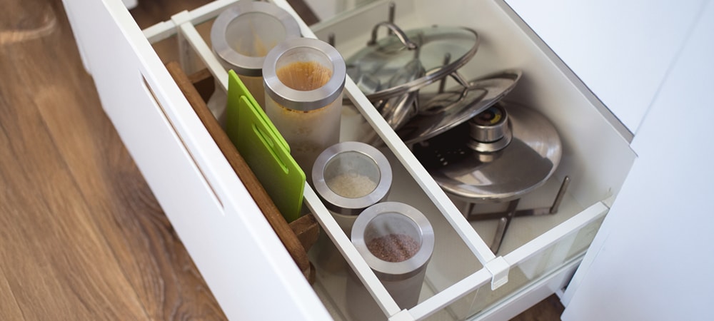 Kitchen drawer with adjustable dividers organizing utensils and dishes